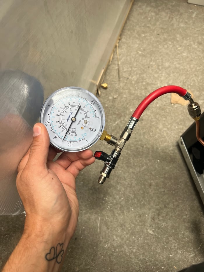 Manometer med rød slange tilkoblet køleanlæg under serviceeftersyn